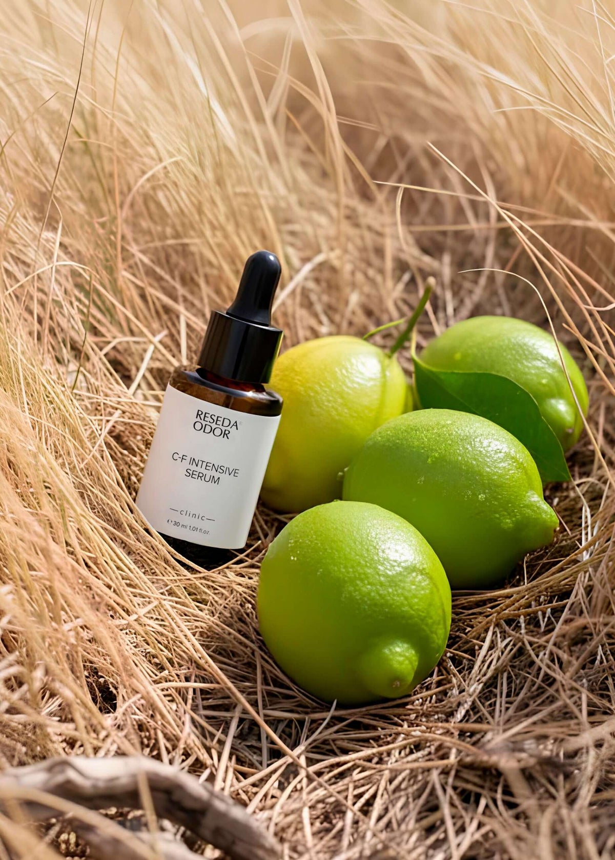 C-F Intensive C Vitamini Serumu şişesi ve yeşil limonlar doğal ortamda, cilt ışıltısı ve koruma için.